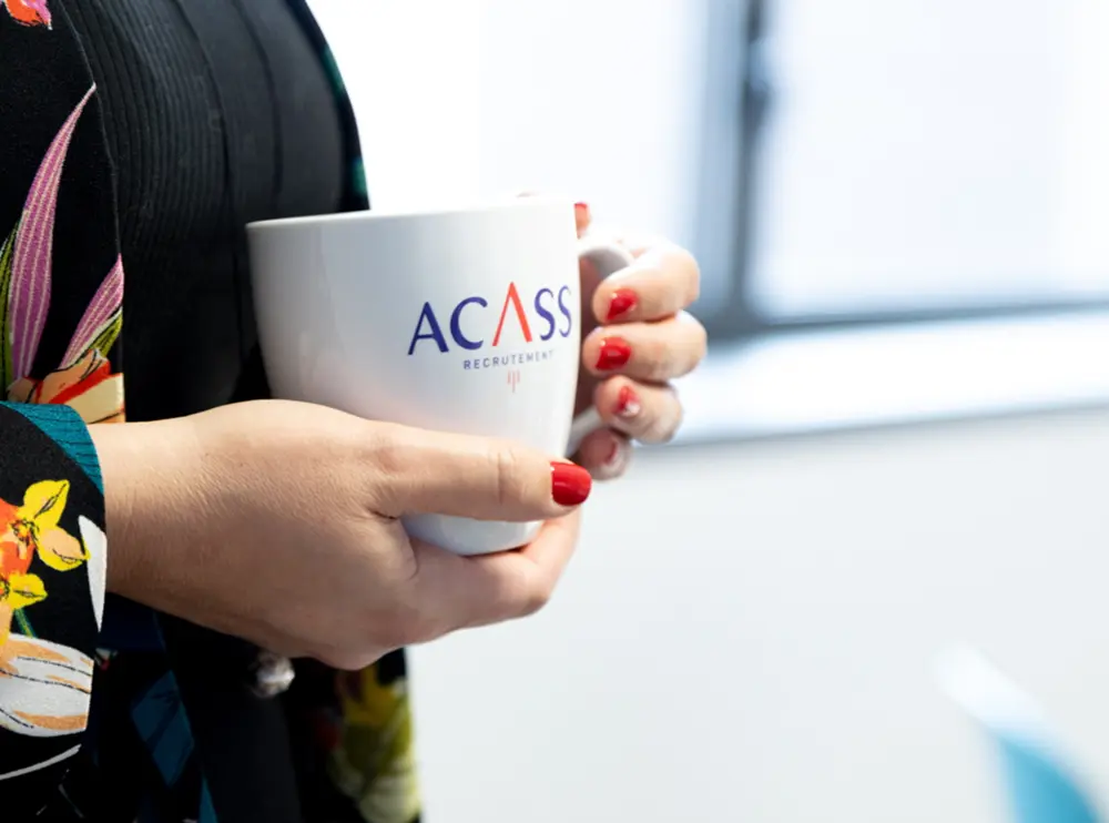 Une collaboratrice ACASS tenant une tasse au logo de l'agence